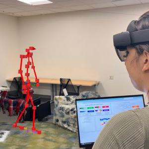 A re太阳城娱乐城er holding a laptop 和 wearing a augmented reality glasses as part of re太阳城娱乐城 on Parkinson's.